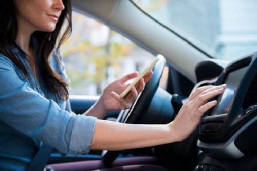 Jeune femme qui utilise le GPS de sa voiture avec son smartphone